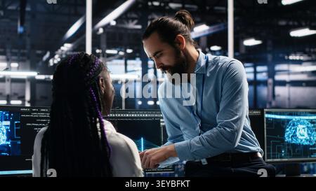 System administrator and employee programs on a computer workstation in a server hub with generative AI assistance. Stock Photo