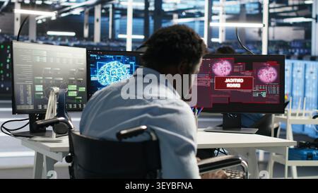 Overworked man in wheelchair upset by error warning popup while reviewing data center AI analytics metrics. Stock Photo