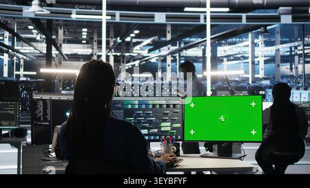 Engineer uses a green screen computer in a server farm to categorize unstructured data with node tree systems. Stock Photo