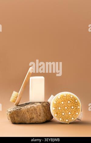 White bar of soap and wooden brushes with natural bristles on wooden pedestal, minimalist beige background. Organic spa care and eco-beauty concept Stock Photo
