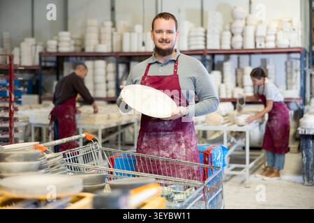 Enthusiastic ceramicist demonstrating handcrafted plates in ceramic studio Stock Photo