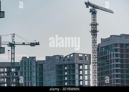 Bustling construction site showcasing early stages of multi-story building, featuring partially completed concrete framework, tower cranes in operatio Stock Photo