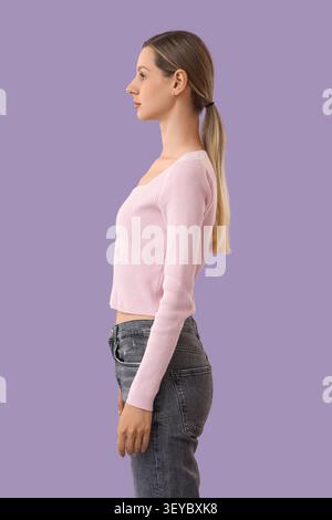 Side profile of young woman with ponytail on purple background Stock Photo