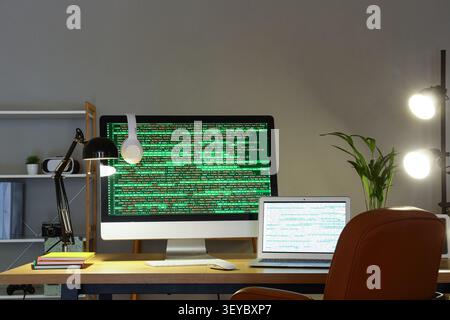 Modern workspace with desktop and laptop displaying code Stock Photo