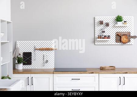 Stylish light kitchen with pegboards and kitchenware Stock Photo