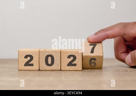Hand flipping of 2026 to 2027 on wooden blocks. Turn of the new year. New year's resolution. Stock Photo