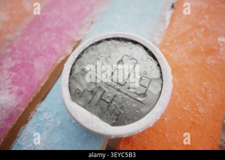 Ice melts on black object on colorful wooden surface Stock Photo