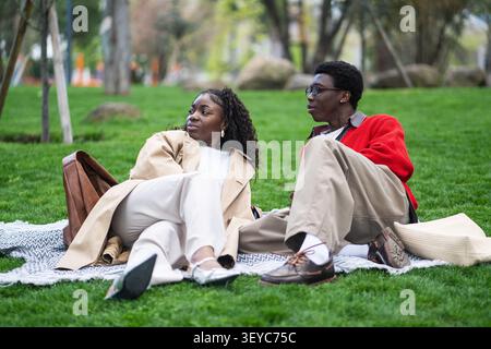 Relaxed carefree african american couple man and woman friends resting outdoors on grass in park. Stock Photo
