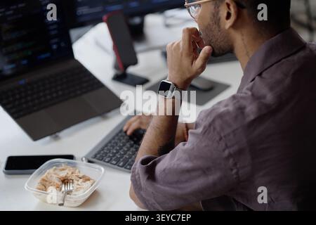 Adult Man Working during Lunch Break in Information Technology Office Stock Photo