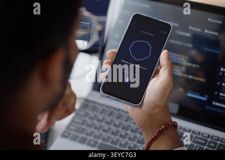 Adult Man Using Voice Assistant on Smartphone in it Office Stock Photo