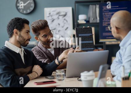 Multiethnic Men Reviewing Software Code in Information Technology Office Stock Photo