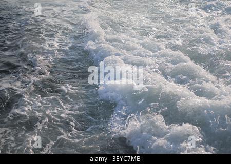 Waves crash on the shore during a sunny day by the ocean Stock Photo