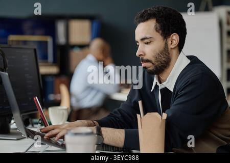 Man Using Laptop for Software Tasks in Information Office Stock Photo