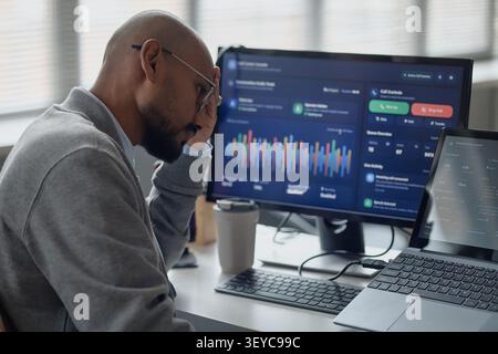 Man Monitoring Data Dashboard in Information Technology Office Stock Photo