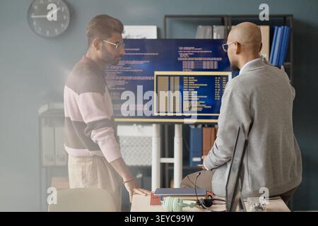 Adult Men Reviewing Software Code on Monitors in it Office Stock Photo
