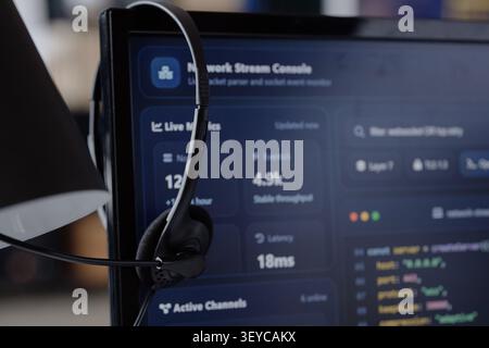 Headset Hanging on Monitor Displaying Network Analytics in IT Office Stock Photo