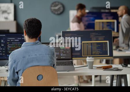 Adult Man Coding at Multiple Monitors in Information Technology Office Stock Photo