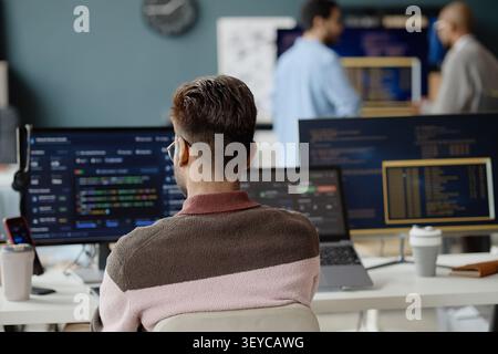 Adult Man Coding at Multi Monitor Workstation in it Office Stock Photo