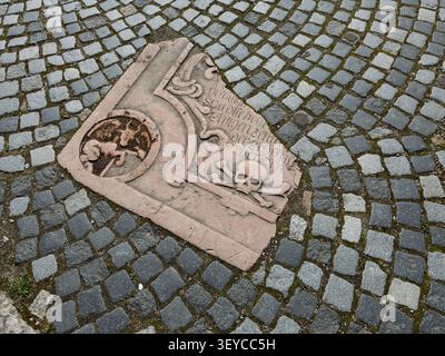 WISMAR, GERMANY - MARCH 30, 2026: An old gravestone fragment embedded in a cobblestone pavement Stock Photo