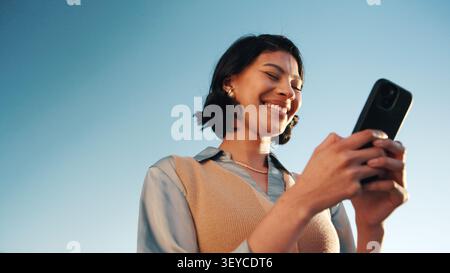 Online, info and woman with phone, outdoor and planning for campaign and brand awareness on website. Creative, social media manager or happy person Stock Photo
