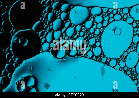 Macro scene shows turquoise bubbles, foam cells, and glossy droplets suspended in dark fluid, creating vivid organic texture for science or design backgrounds Stock Photo