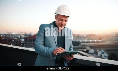 Happy, man and construction contractor with tablet for city planning, research or site development. Reading, digital technology and civil engineer Stock Photo