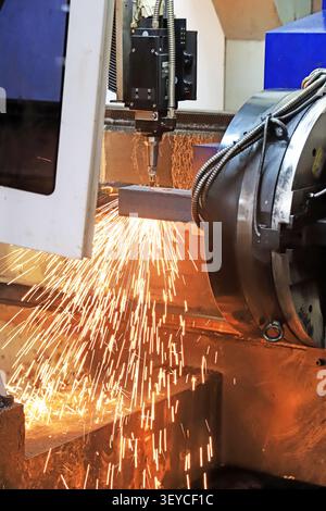A dynamic close-up of a CNC laser cutting machine in operation, precisely slicing through a solid steel bar and releasing a spectacular cascade of bri Stock Photo
