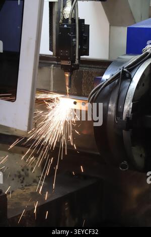 A dramatic close-up of a CNC plasma cutting machine in action, precisely drilling holes into a steel channel profile while emitting a brilliant burst Stock Photo