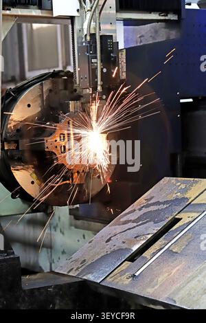 A high-energy close-up of a CNC plasma cutting machine in full operation, releasing a brilliant, radiating burst of white-hot sparks as it cuts throug Stock Photo