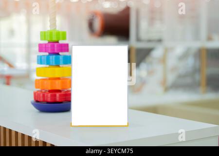 Displaying blank menu frames in kid's playground, Booklet Stands, White Paper Sheets, And Acrylic Tent Card On Table Setting. Copy space. Stock Photo