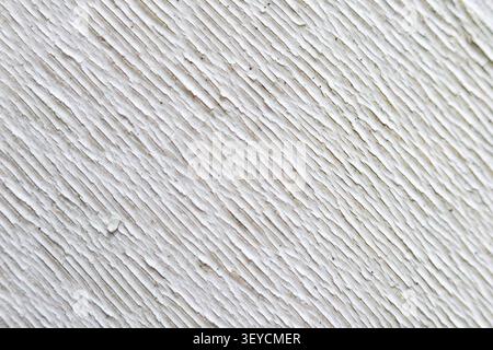A white textured wall surface with diagonal rough plaster lines creating pattern, showing detail and depth in construction material Stock Photo