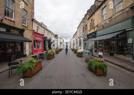 A solitary scooterist rides down a quiet, pedestrianized Princess Victoria Street lined with historic shops and planters in Clifton, Bristol. Stock Photo