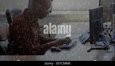 Man placing hands on keyboard, coding and leaning forward at tech desk, binary overlay appearing Stock Photo