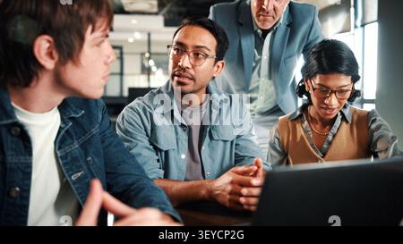 Laptop, meeting and business people in office with feedback on software development project. Discussion, review and team of web designers with manager Stock Photo