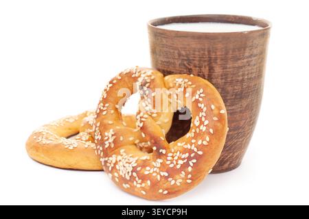 Traditional German pretzel with sesame seeds and clay cup of fresh milk isolated on clean white background Stock Photo