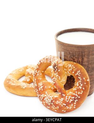 Traditional German pretzel with sesame seeds and clay cup of fresh milk isolated on clean white background upper copy space template Stock Photo