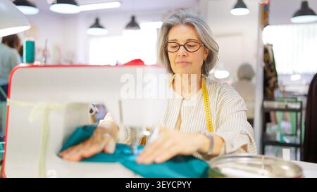 Mature woman sewing fabric in creative workshop Stock Photo