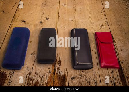 A selection of coloured cases made from different materials for the transport and protection of spectacles or glasses placed on a wooden background Stock Photo