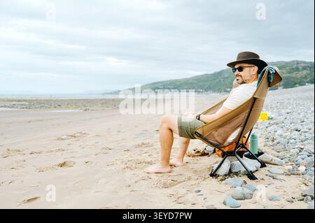 Man sitting in a camping chair on a quiet beac Stock Photo