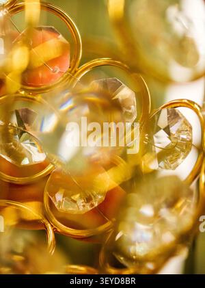 Abstract macro of faceted crystal ornaments framed by golden rings with warm glowing reflections, soft focus and sparkling luxury background. Stock Photo