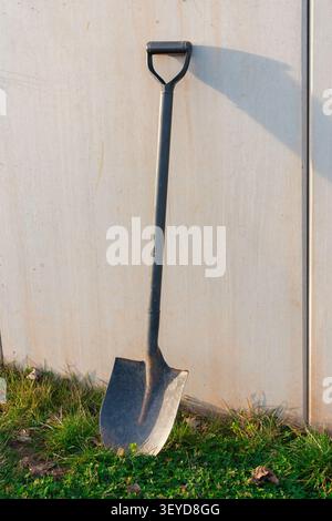 A black iron paw sculpture leans against a textured concrete wall on a bright sunny day. The contrast between the dark metal and the light concrete Stock Photo