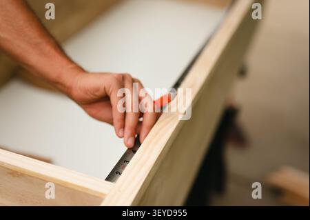 Person carefully measures a wooden plank with pencil and ruler Stock Photo