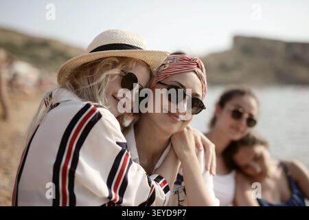 Happy young friends hugging on a sunny beach Stock Photo