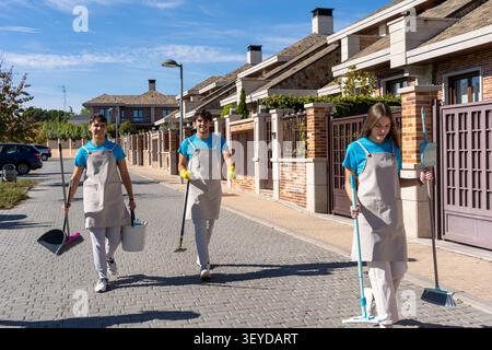 Professional cleaning service team members walking on a street with cleaning tools and equipment Stock Photo
