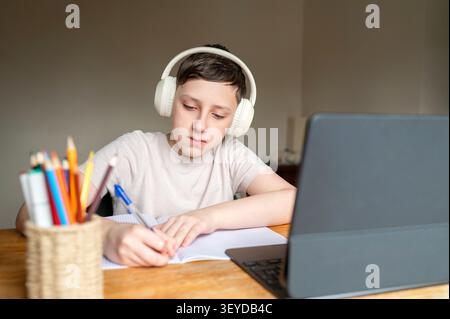 Focused schoolboy concentrating on homework during online class Stock Photo