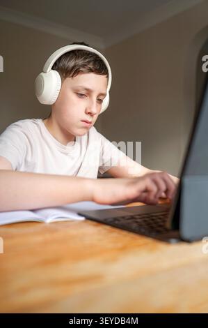 Focused schoolboy typing on laptop during home study Stock Photo