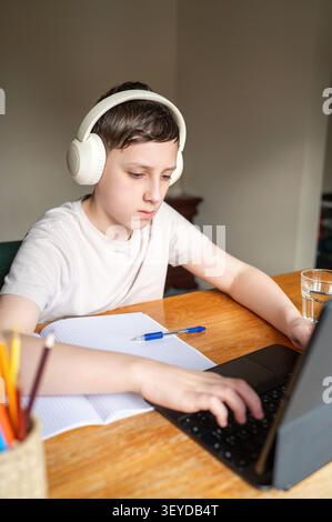 Schoolboy using laptop during online lesson at home Stock Photo