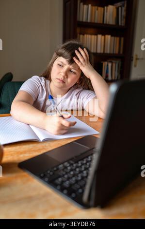 Frustrated schoolgirl studying from home with laptop Stock Photo
