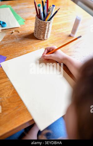 Over shoulder view of child hand on a blank sheet of paper Stock Photo