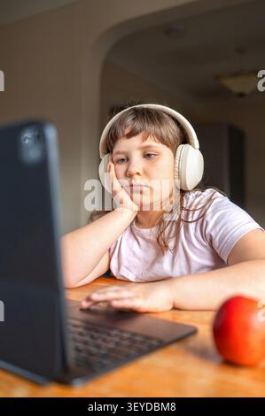 Unhappy schoolgirl attending online class at home Stock Photo